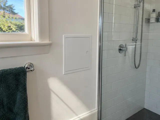 Neat white access panel beside a tiled shower and painted bathroom wall in Kirribilli